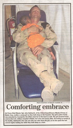 Soldier sits and rocks an injured Iraqi Child