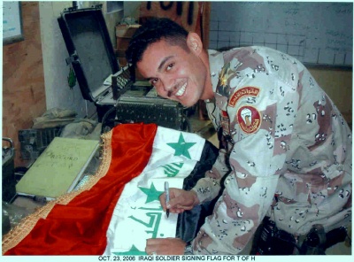 Iraqi Solider signing Iraqi Flag